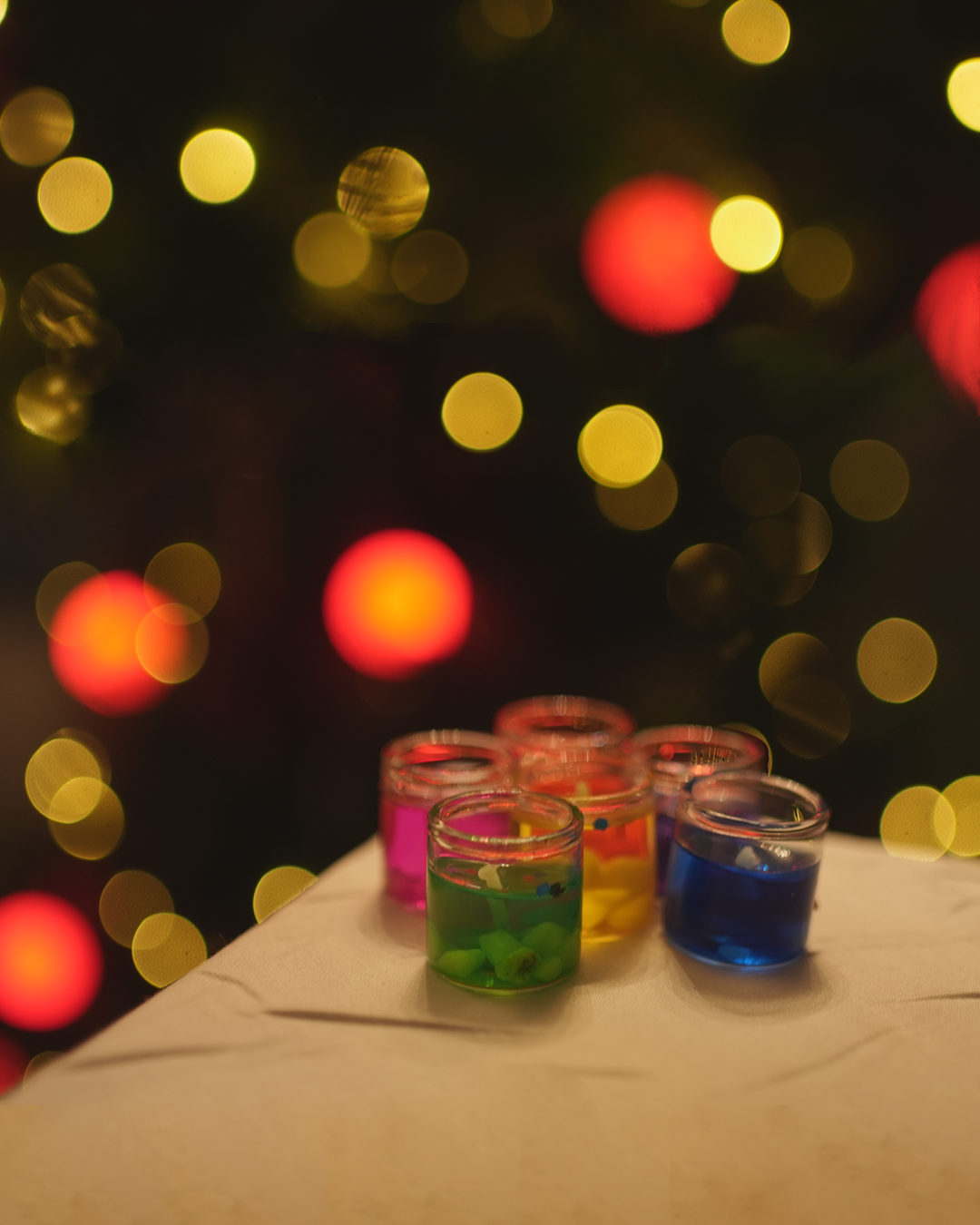 Colorful votive candles or wax melts, with a festive bokeh background