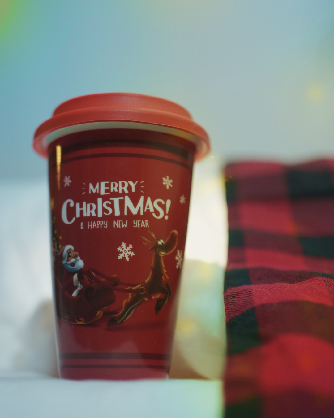 Festive red ceramic mug with a lid, featuring Santa Claus flying with reindeer and the text 'Merry Christmas! & Happy New Year'