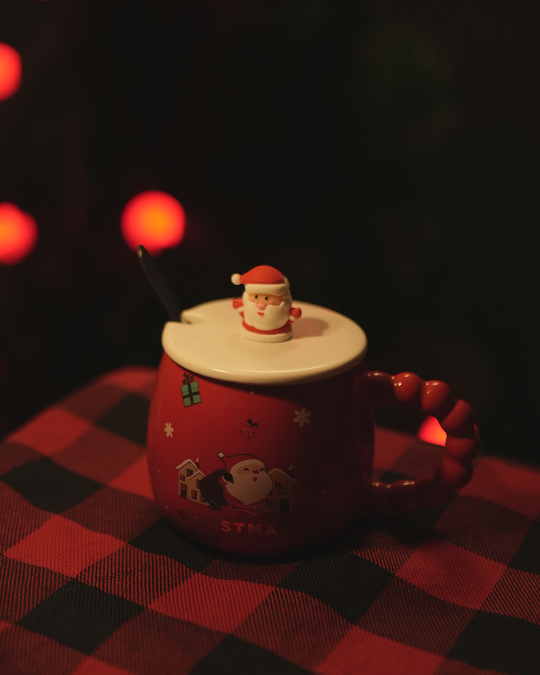 Festive Christmas mug with Santa lid and holiday decorations.
