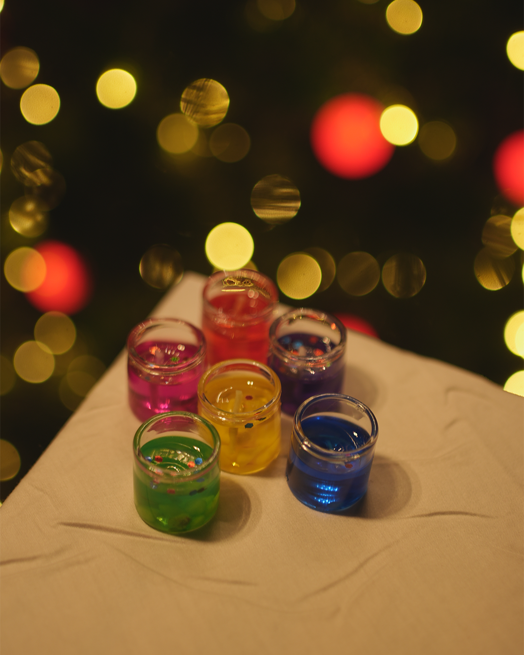 Small glass containers filled with different colorful gel wax candles. Tiny and cute for home decor.