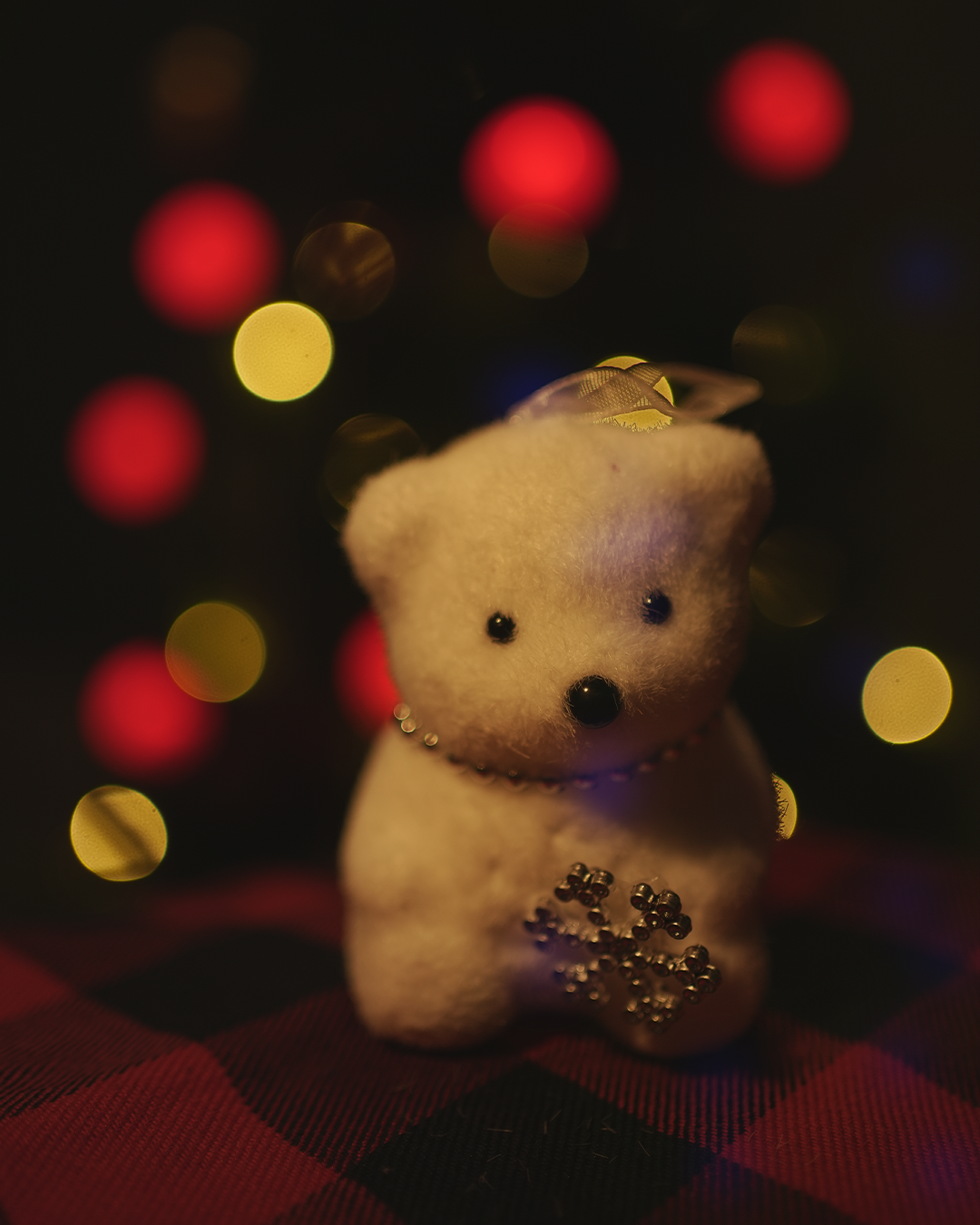 Christmas bear ornament with gold accents and bokeh lights.